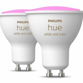 Das Bild zeigt zwei Philips Hue White & Color Ambiance GU10 Glühbirnen mit einer Helligkeit von 230 Lumen. Die Lampen sind weiß mit einer beleuchteten Farboberseite, wodurch angedeutet wird, dass sie in der Lage sind, verschiedene Farben zu erzeugen. Das Philips Hue Logo ist deutlich auf dem vorderen Teil der Lampen sichtbar. Der Zweck des Bildes ist es, das Design und die Farbfunktionen der smarten Philips Hue Glühbirnen zu präsentieren.