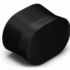 Das Bild zeigt den Sonos Era 300 Multiroom-Lautsprecher in schwarzer Farbe, der auf einer hellen Oberfläche steht. Das Design ist modern und stilvoll, mit einer abgerundeten, kantigen Form und einer strukturierten Oberfläche. Auf der Oberseite des Lautsprechers befinden sich Touch-Bedienelemente. Das Logo "SONOS" ist auf der Front des Lautsprechers sichtbar. Der Zweck des Bildes ist es, das Produkt visuell darzustellen und Details wie Design, Farbe und Bedienelemente zu zeigen.
