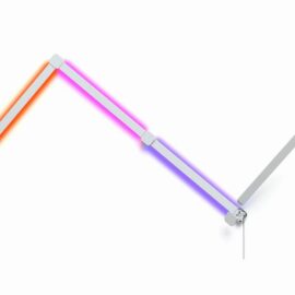 Das Bild zeigt einen Teil des 'Nanoleaf Lines Squared Starter Kit', bestehend aus modularen LED-Lichtleisten, die in einem Winkel angeordnet sind, um die flexible Anpassbarkeit und Farbdarstellung der Beleuchtung zu demonstrieren. Die Lichtleisten sind in verschiedenen Farbtönen beleuchtet – von Orange über Pink bis hin zu Lila – und heben die Fähigkeit des Produkts zur Erstellung individueller Beleuchtungsszenarien hervor. Die Verbindungsstücke zwischen den Leisten sind deutlich sichtbar, was die modulare Natur und einfache Erweiterbarkeit des Systems unterstreicht. Ein Kabel ist an dem zuletzt sichtbaren Modul angebracht, was auf die Stromversorgung hinweist.