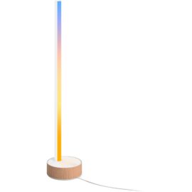 Das Bild zeigt die 'Gradient Signe Tischleuchte', eine LED-Leuchte mit einem schlanken, vertikal orientierten Leuchtstab auf einer runden Holzbasis. Die Leuchte zeigt einen farbverlaufenden Effekt von Blau zu Gelb. Ein weißes Stromkabel führt von der Basis weg. Das Bild dient zur visuellen Präsentation des Designs und der Farbwirkung der Leuchte.