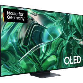Das Bild zeigt den OLED-Fernseher GQ-55S95C von Samsung mit einem scharfen und farbintensiven Display, auf dem abstrakte grüne Wellen zu sehen sind. Ein Aufkleber mit der Aufschrift "Made for Germany" ist auf dem Bildschirm angebracht, was darauf hinweist, dass das Produkt speziell für den deutschen Markt hergestellt oder angepasst wurde. Der Fernseher ist auf einem Standfuß montiert und das OLED-Symbol ist deutlich im unteren Bildschirmbereich zu sehen, was die Bildtechnologie des Displays hervorhebt. Das Bild soll die hohe Bildqualität und das elegante Design des Fernsehers veranschaulichen.