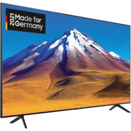 Das Bild zeigt einen LED-Fernseher des Modells GU-43TU6979. Im Fokus steht das scharfe und farbenprächtige Display, auf dem eine beeindruckende Landschaft mit einem verschneiten Berg und einem blauen Himmel zu sehen ist. Die Bildqualität des Fernsehers wird betont, und das Siegel "2021 Made for Germany" weist darauf hin, dass das Produkt für den deutschen Markt konzipiert wurde. Der Fernseher selbst hat ein schmales Rahmen-Design und steht auf zwei kleinen Standfüßen.