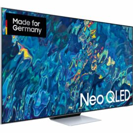 Das Bild zeigt den Neo QLED GQ-55QN95B QLED-Fernseher von Samsung in schräger Frontansicht. Auf dem Display ist eine lebendige, abstrakte Farbkomposition zu sehen, die die Bildqualität des Fernsehers hervorheben soll. Der Fernseher hat einen schlanken Rahmen und steht auf einem zentralen, schmalen Standfuß. Oben links auf dem Bildschirm ist ein Label mit der Aufschrift "Made for Germany" platziert. Im Vordergrund des Bildes wird die Markenbezeichnung "Neo QLED" prominent eingeblendet. Das Bild dient dem Zweck, das Produkt in einem ansprechenden Licht zu präsentieren und seine Designqualitäten sowie die Displaytechnologie hervorzuheben.